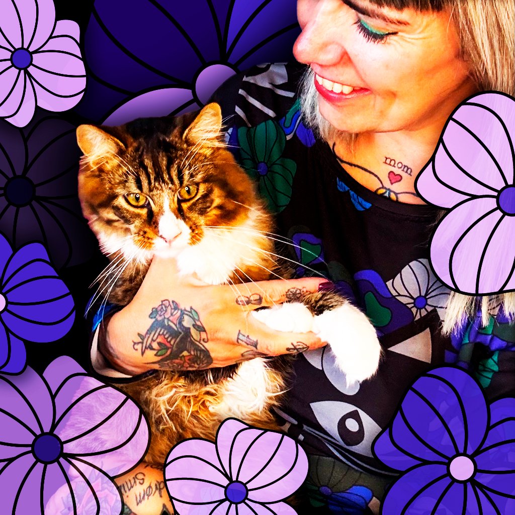 A woman holding her precious cat and wearing the MAGICAT mystic midi dress by SHALMIAK. Photo decorated with lovely purple flowers.