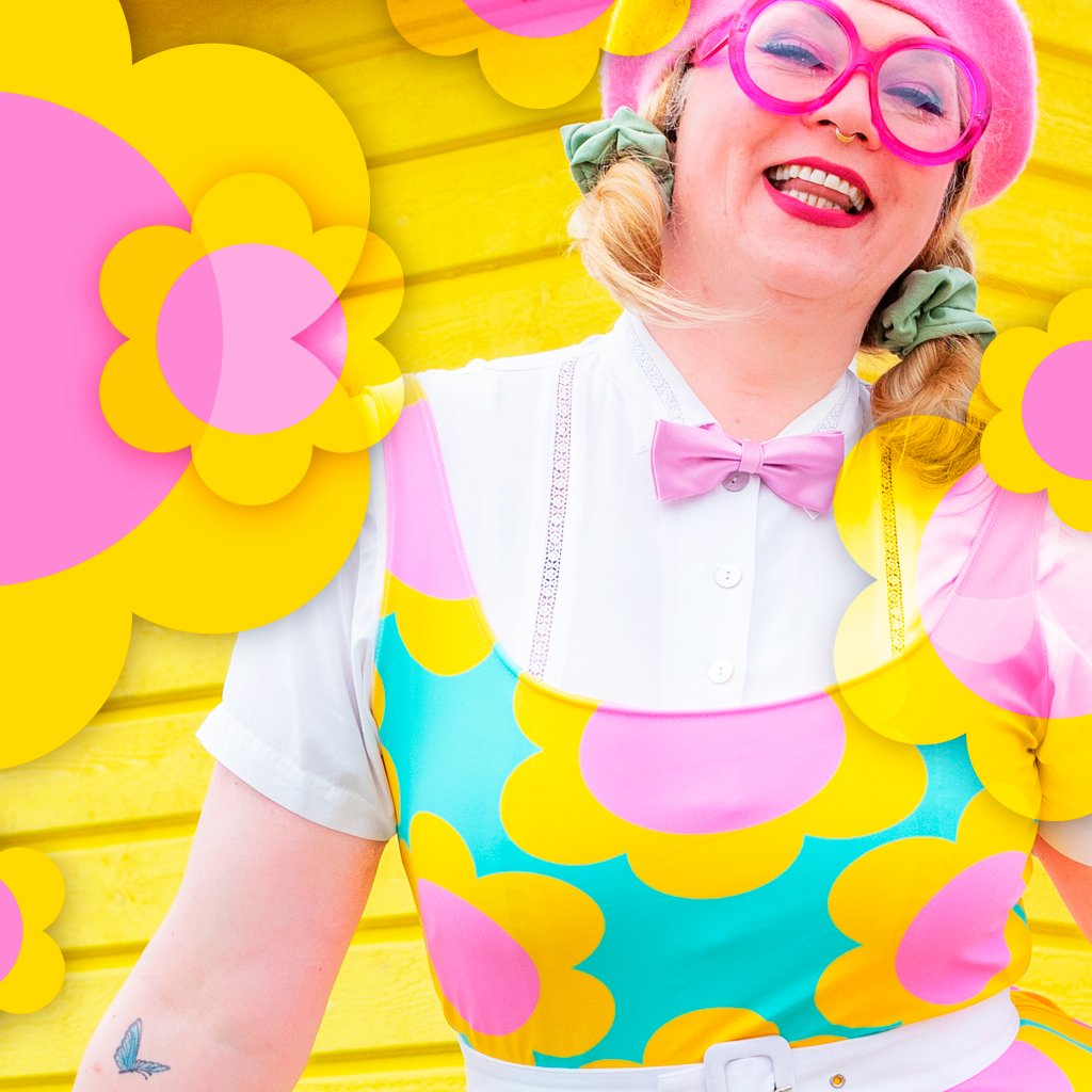 A smiling woman wearing a colorful dress with yellow flowers.