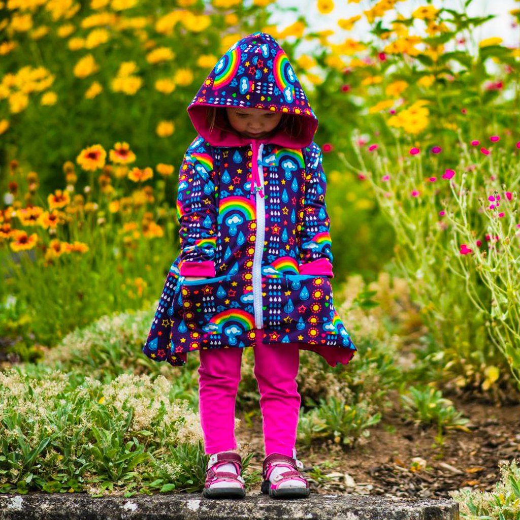 A little girl among summer flowers dressed in a RAINBOWPHANT coat. Photo by Nähfrosch.