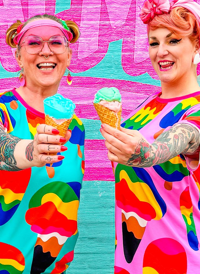 Two cheerful women holding ice cream cones in bold MANIC ICE t-shirt dresses by SHALMIAK.